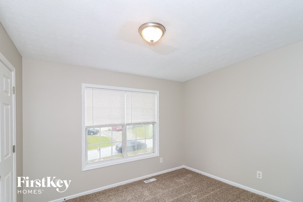 a bedroom with a large window and a carpeted floor