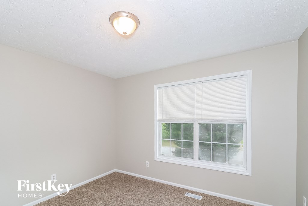 a bedroom with a large window and a carpeted floor