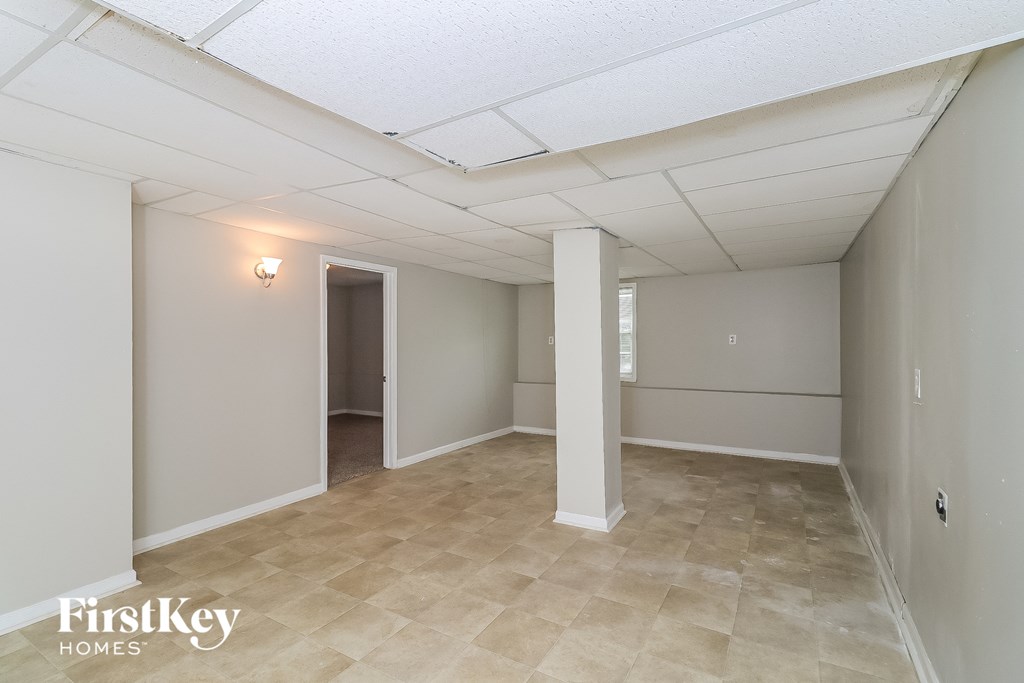 the living room and dining room of an apartment with a tile floor and white walls