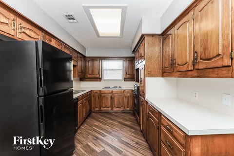 a kitchen with wooden cabinets and a black refrigerator