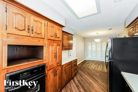 A kitchen with wooden cabinets and a black fridge.