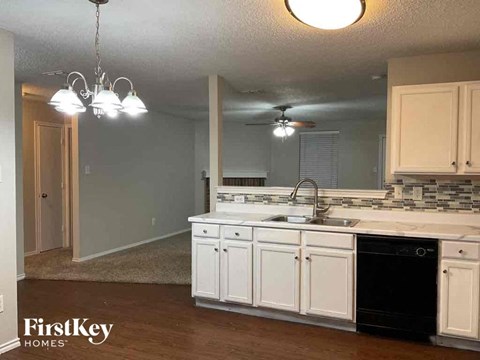 A kitchen with white cabinets and a black dishwasher.