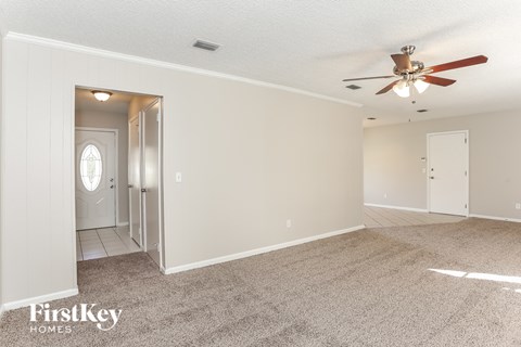 a living room with carpet and a ceiling fan