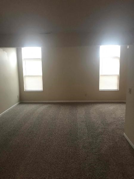 an empty room with two windows in it