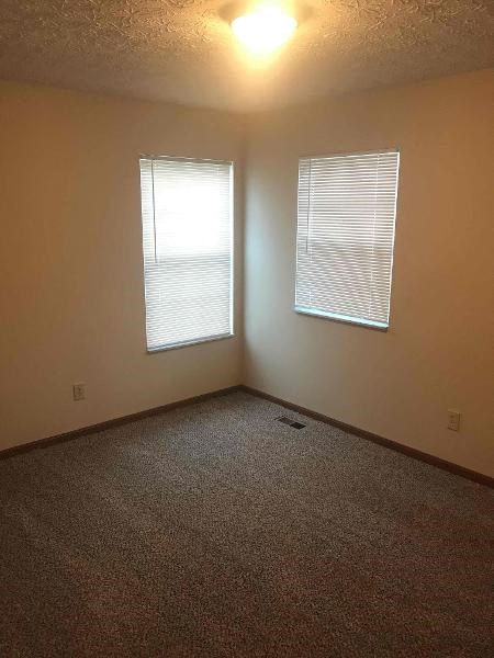 an empty room with a window and a carpet