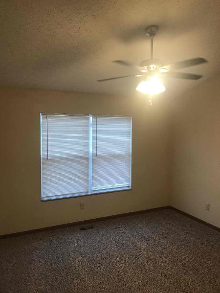 an empty room with a ceiling fan and a window