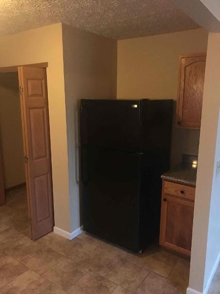a kitchen with a black refrigerator and a door