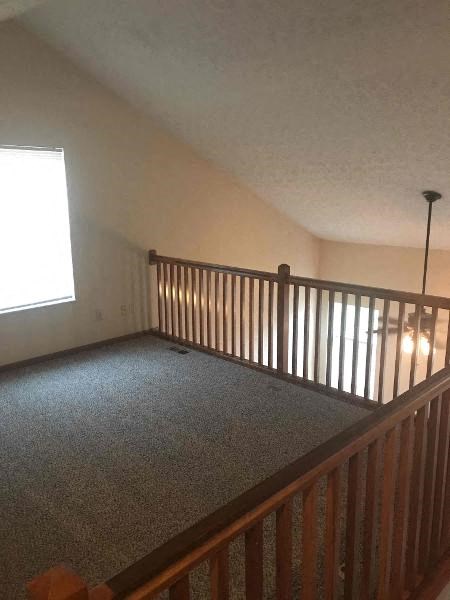 a upstairs room with a railing and a window
