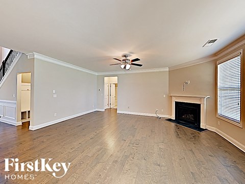A spacious living room with wood flooring and a fireplace.