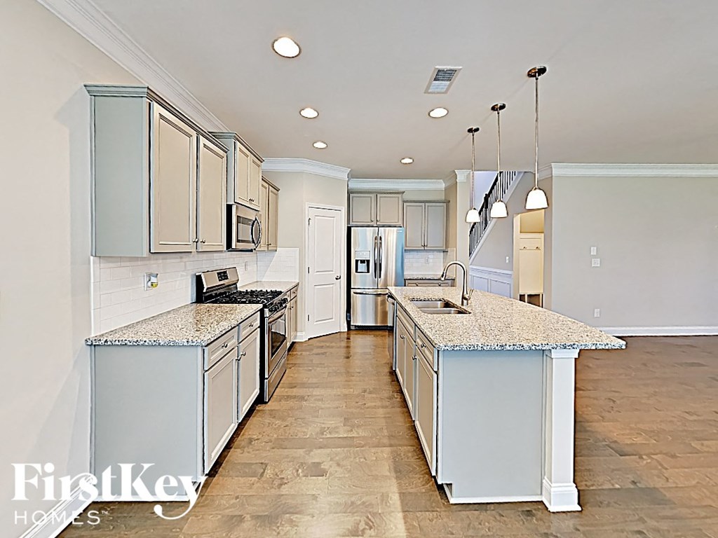 A kitchen with a granite counter top and wooden floors.