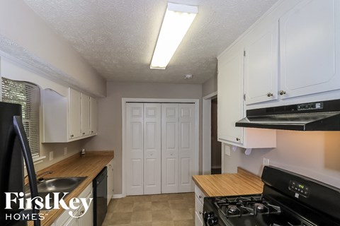 A kitchen with a stove top oven and cabinets.