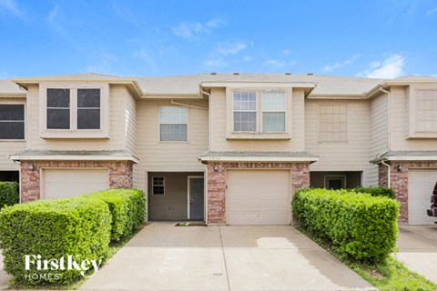 a beige house with two garage doors and a driveway