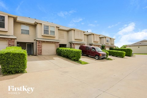 a beige house with a red van parked in the driveway