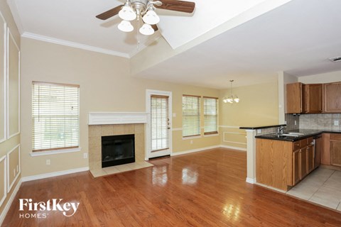 an empty living room with a fireplace and a kitchen