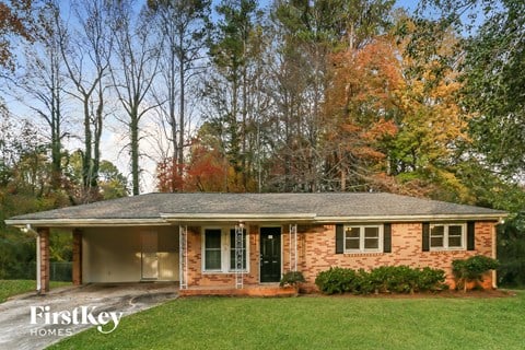 front view of a brick house with a lawn and trees