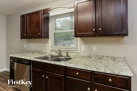 a kitchen with dark wood cabinets and granite counter tops and a sink