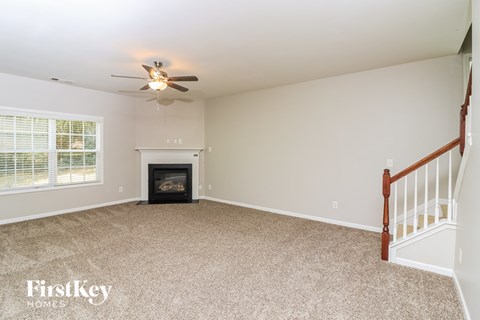 A living room with a fireplace and a ceiling fan.