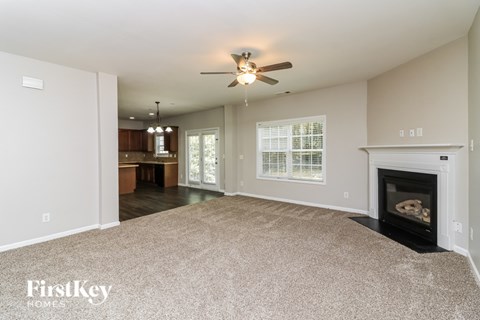 A spacious living room with a fireplace and a ceiling fan.