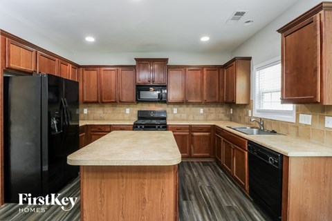 A kitchen with wooden cabinets and a black fridge.