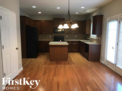 A kitchen with wooden floors and a chandelier.