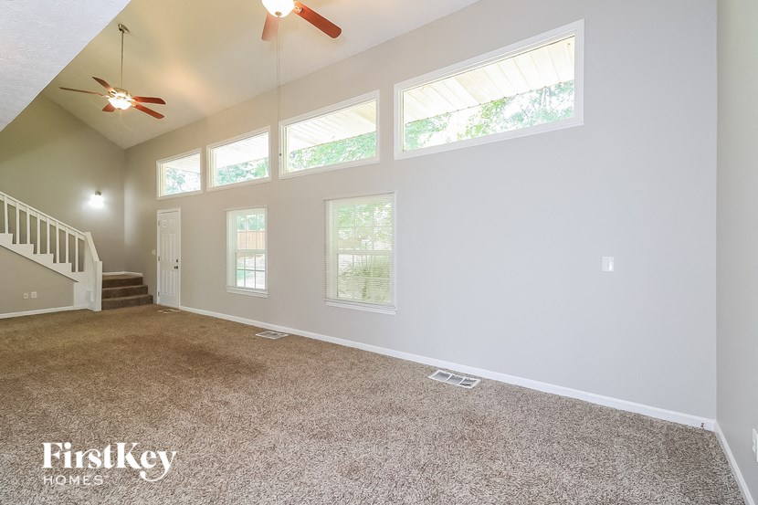A spacious room with a carpeted floor and a staircase leading to the upper level.