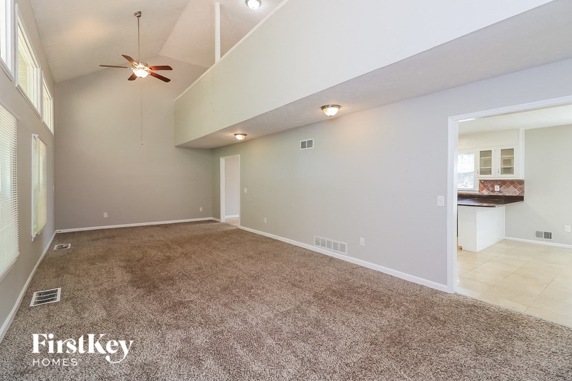 A spacious room with a carpeted floor and a ceiling fan.