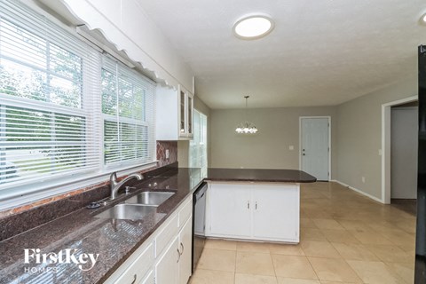 A kitchen with a sink and a window with blinds.