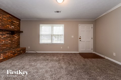 A room with a brick fireplace and a carpeted floor.
