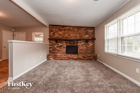 A room with a brick fireplace and a carpeted floor.