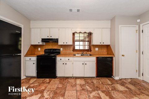 A kitchen with a black fridge and a black dishwasher.