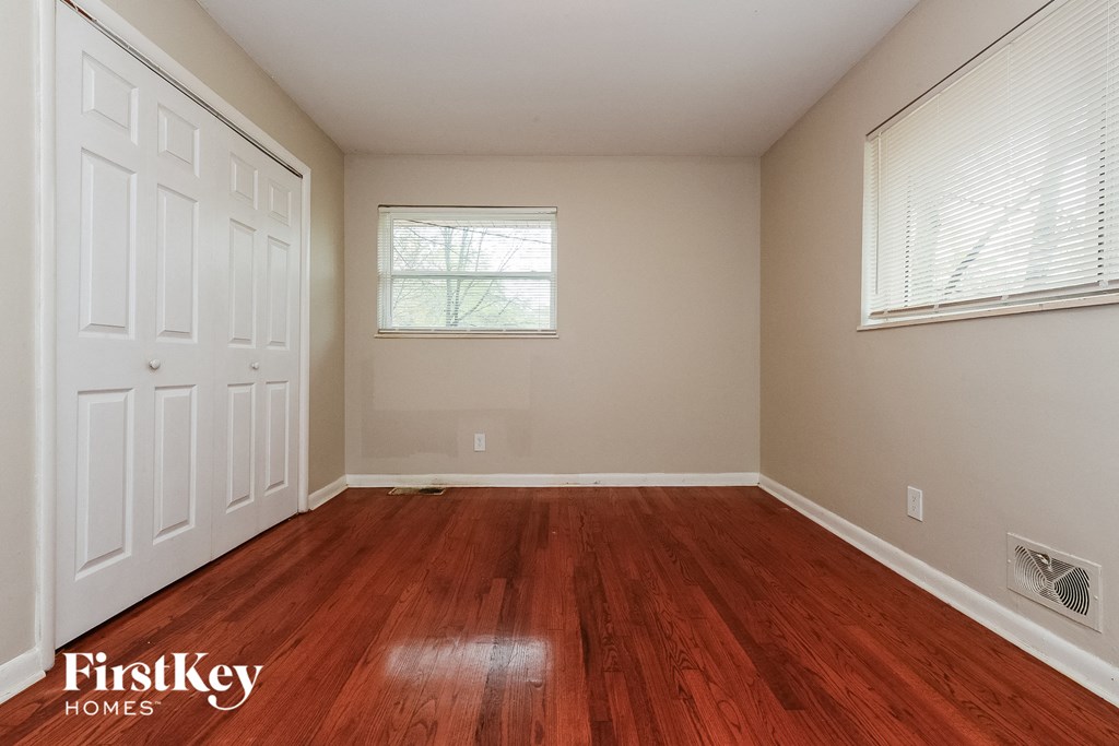 a bedroom with wood floors and a white door and window