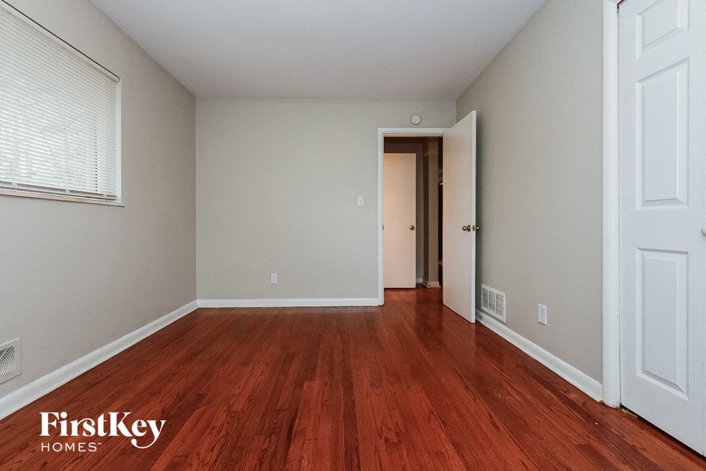 a bedroom with wood flooring and a door to a hallway