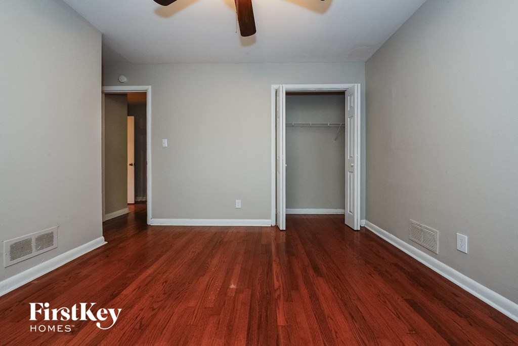 a bedroom with wood flooring and a closet and a ceiling fan