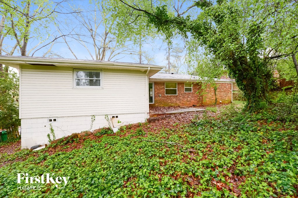 a small white house with a brick house behind it