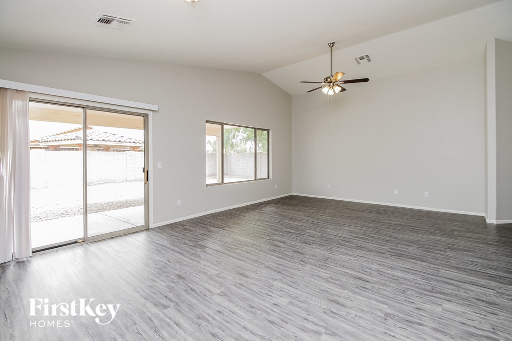 an empty living room with a ceiling fan and sliding glass doors