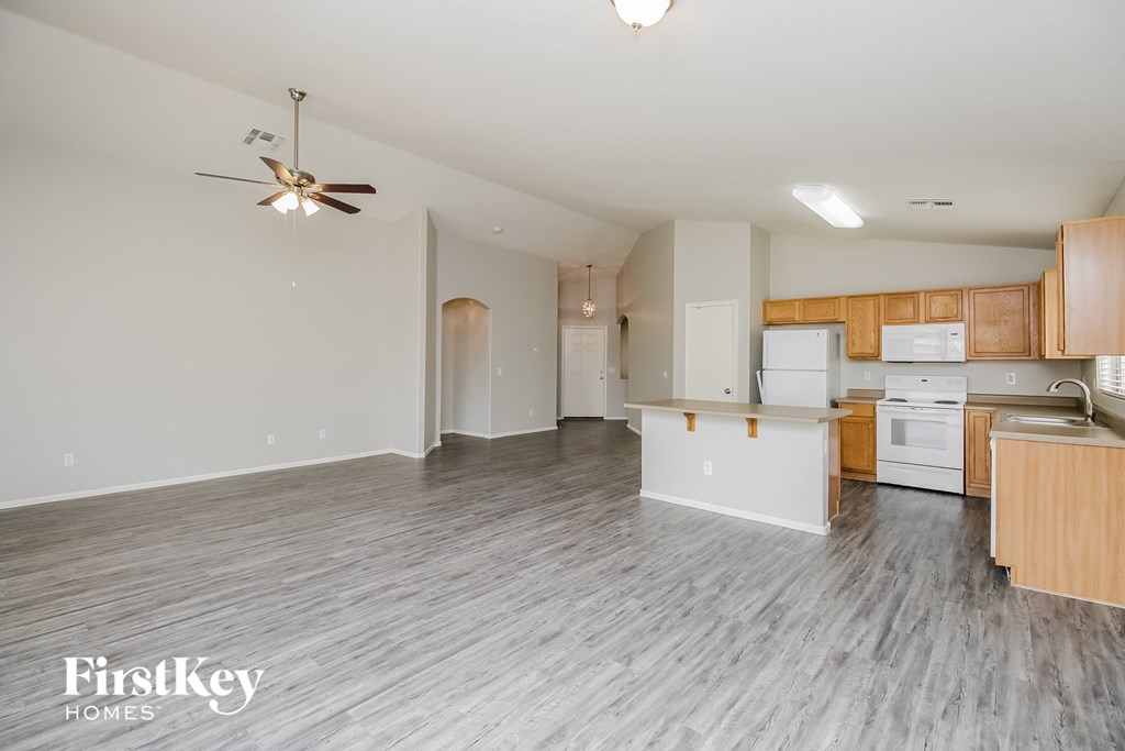 a kitchen and living room with wood flooring and a ceiling fan