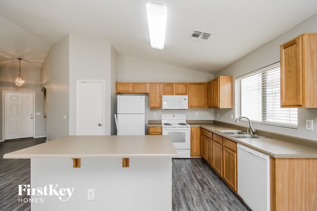an empty kitchen with white appliances and wooden cabinets