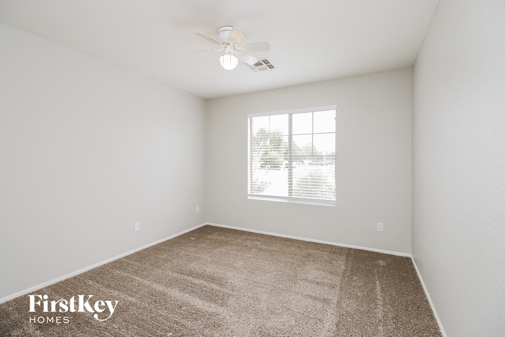 a spacious bedroom with carpet and a ceiling fan