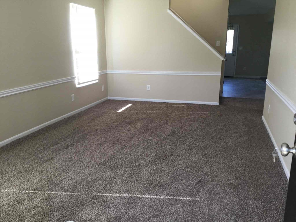 a carpeted living room with white walls and a gray carpet