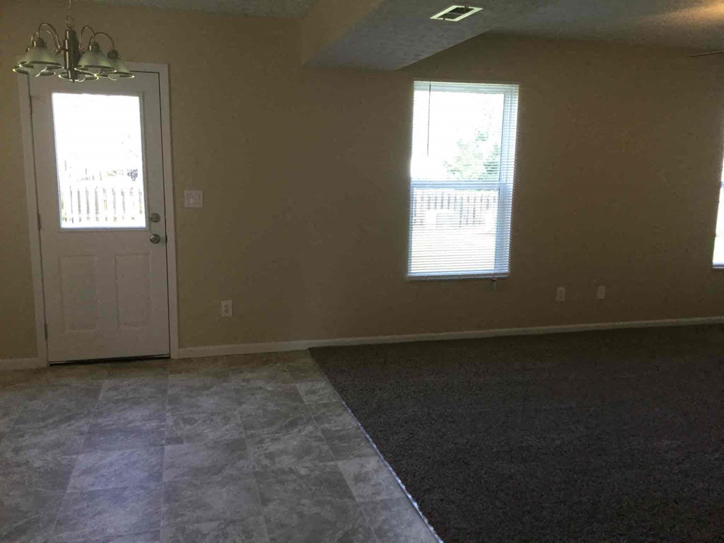 an empty living room with a door and window