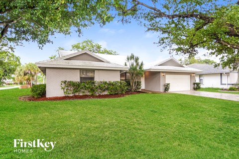 A well-maintained lawn in front of a house with the logo "FirstKey HOMES" on the bottom left.