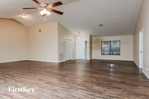 A spacious room with wooden floors and a ceiling fan.