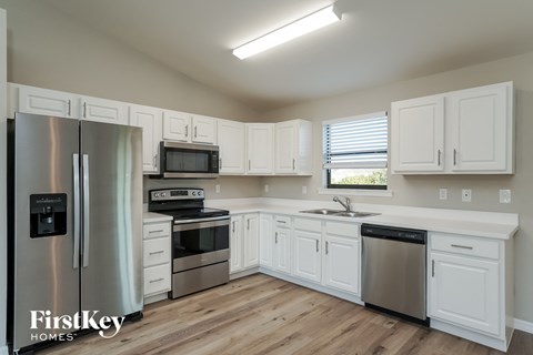 A kitchen with white cabinets and a stainless steel refrigerator.