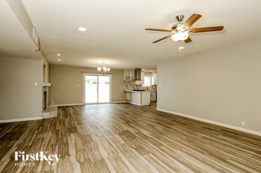 an empty living room with wood floors and a ceiling fan
