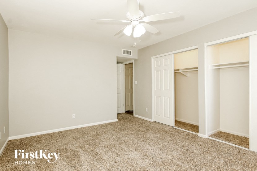 a bedroom with three closets and a ceiling fan