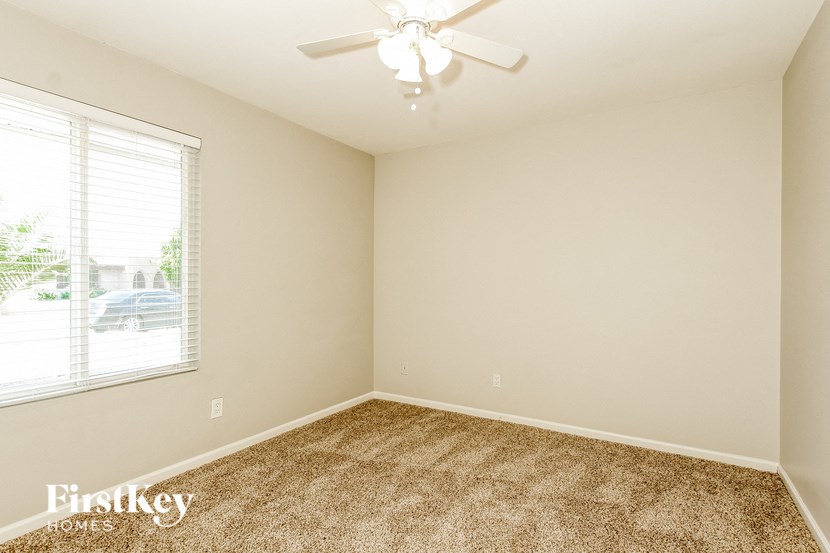 a bedroom with a ceiling fan and a large window