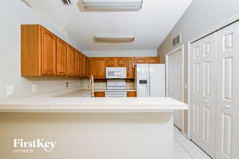 a kitchen with white countertops and wooden cabinets and white appliances