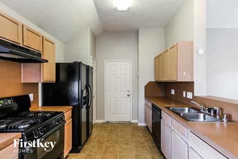 A kitchen with a black fridge and a black stove top.