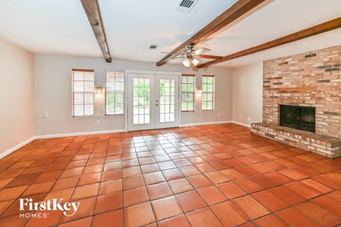 A large empty room with a fireplace and a tiled floor.