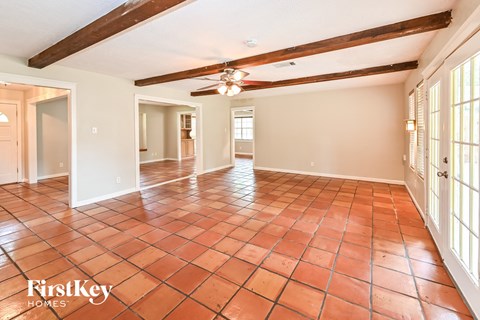 A spacious room with a tiled floor and wooden beams on the ceiling.